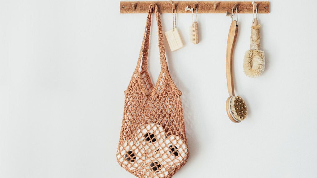 A bathroom hanger with soap, wooden scrubbing brushes and a resuable bag holding toilet paper rolls.