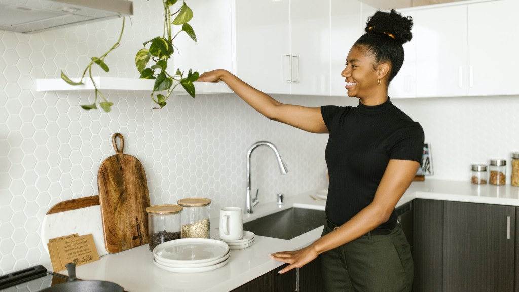 Person in kitchen smiling while they tidy up for a spring clean.