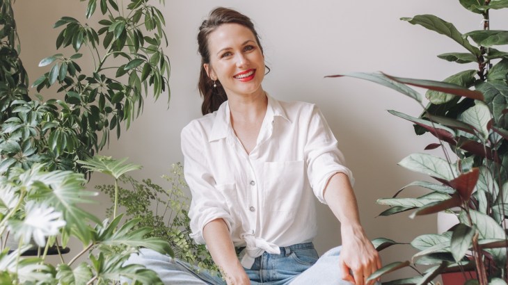 KonMari Consultant Sally Flower sits among a tidy room filled with houseplants.