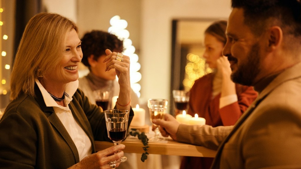 Family and friends at a Christmas gathering with fairy lights and wine, discussing recycling and sustainability.