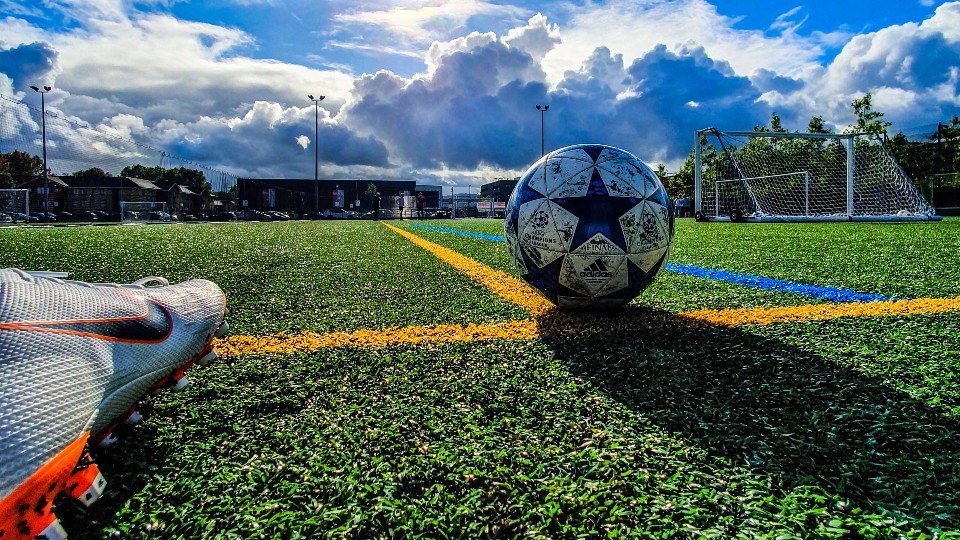 Dirty soccer ball on a sunny pitch about to be kicked at the goal.